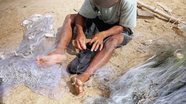 Kampong - Camboya - 03-02 - 2015: Primer plano de un pescador sentado en la orilla del río para reparar una red a mano — Vídeo de stock