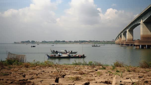 Liten fiskebåt vid floden passerar under en bro. Fiskarnas båtar drar ett stort netto ur vattnet som bakgrund — Stockvideo