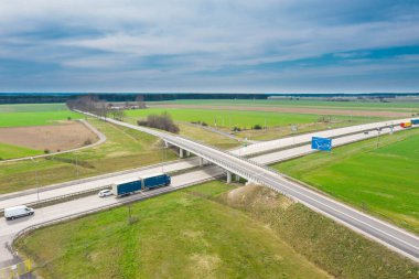 Anayol çok yüksek bir yerden görülmektedir. İki gri beton yol. Kenarlarda tarlalar var. Fotoğraf uçan bir drondan alındı..
