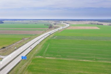 Anayol çok yüksek bir yerden görülmektedir. İki gri beton yol. Kenarlarda tarlalar var. Fotoğraf uçan bir drondan alındı..
