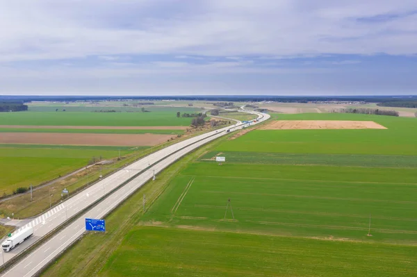 Anayol çok yüksek bir yerden görülmektedir. İki gri beton yol. Kenarlarda tarlalar var. Fotoğraf uçan bir drondan alındı..