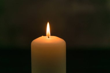 Karanlığın aleviyle parlayan beyaz bir mum.