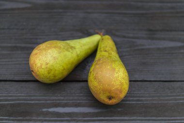 Siyah bir ahşap döşemeye iki armut..