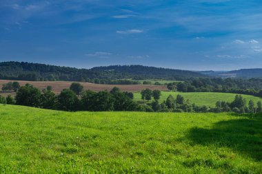 Sudeten etekleri. Çayırlarla, çayırlarla, ağaç kümeleriyle kaplanmış dalgalı bir arazi. Uzakta ufukta dağları görebilirsin. İHA 'dan fotoğraf..