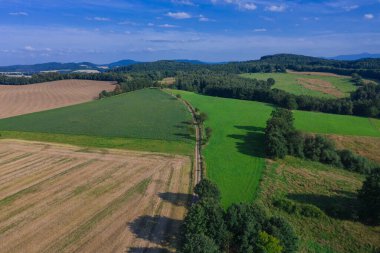 Sudeten etekleri. Çayırlarla, çayırlarla, ağaç kümeleriyle kaplanmış dalgalı bir arazi. Uzakta ufukta dağları görebilirsin. İHA 'dan fotoğraf..