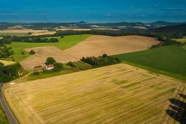 Sudeten etekleri. Çayırlarla, çayırlarla, ağaç kümeleriyle kaplanmış dalgalı bir arazi. Uzakta köyün binalarını ve ufukta dağları görebilirsiniz. İHA 'dan fotoğraf..