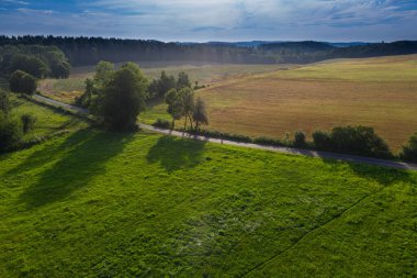 Sudeten etekleri. Çayırlarla, çayırlarla, ağaç kümeleriyle kaplanmış dalgalı bir arazi. Uzakta ufukta dağları görebilirsin. İHA 'dan fotoğraf..