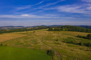 Sudeten etekleri. Çayırlarla, çayırlarla, ağaç kümeleriyle kaplanmış dalgalı bir arazi. Uzakta ufukta dağları görebilirsin. İHA 'dan fotoğraf..