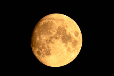 Ay bulutsuz siyah gökyüzünde yumuşak sarı ışıkla parlar. Ay son çeyrekte..