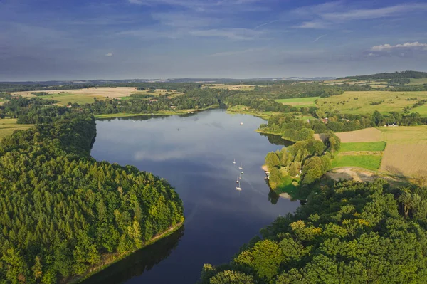 A water reservoir, a reservoir near the town of Lesna in the south-west of Poland. You can see the sailboats moored. The shores are covered with a dense forest. View from the drone.