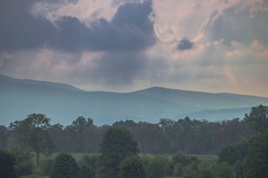 Ovadaki tarlalar ve çayırlar. Ufuktaki Karkonosze Dağlarının sisli zirveleri.
