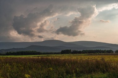Uçsuz bucaksız bir düzlük, Sudeten etekleri tarıma elverişli tarlalar ve çayırlarla kaplıdır. Gökyüzü hafif bulutlu, bulutların arasından güneş ışığı çizgileri görülebilir. Ufukta sisli dağ tepelerini görebilirsiniz. Bunlar Karkonosze Dağları..