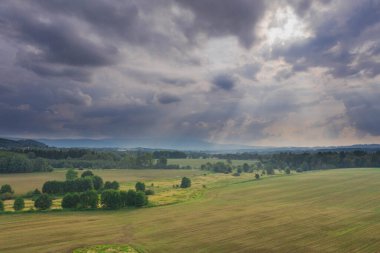 Ovadaki tarlalar ve çayırlar. Ufuktaki Karkonosze Dağları 'nın sisli zirveleri. İnsansız hava aracından görüntüle.