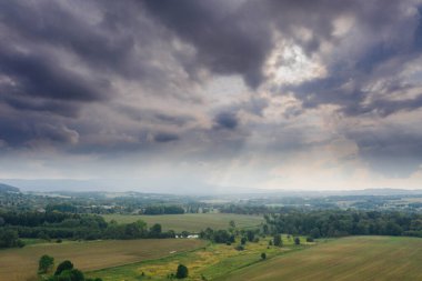 Ovadaki tarlalar ve çayırlar. Ufuktaki Karkonosze Dağları 'nın sisli zirveleri. İnsansız hava aracından görüntüle.