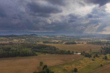 Ovadaki tarlalar ve çayırlar. Ufuktaki Karkonosze Dağları 'nın sisli zirveleri. İnsansız hava aracından görüntüle.