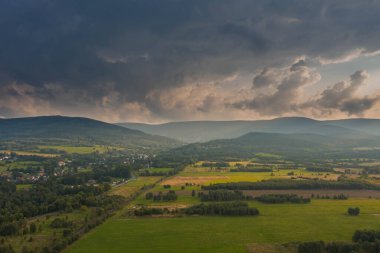 Ovadaki tarlalar ve çayırlar. Ufuktaki Karkonosze Dağları 'nın sisli zirveleri. İnsansız hava aracından görüntüle.