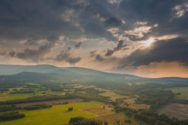 Ovadaki tarlalar ve çayırlar. Ufuktaki Karkonosze Dağları 'nın sisli zirveleri. İnsansız hava aracından görüntüle.