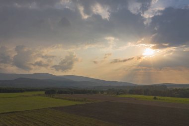 Ovadaki tarlalar ve çayırlar. Ufuktaki Karkonosze Dağları 'nın sisli zirveleri. İnsansız hava aracından görüntüle.