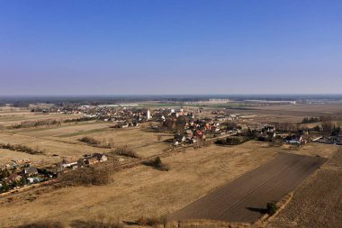 Uçsuz bucaksız bir düzlük, çok yüksek bir yerden görülen tarım arazileri ve çayırlarla kaplıydı. Batı Polonya 'nın agaski ilçesindeki Konin agaski köyünün binaları uzaktan görülebilmektedir..