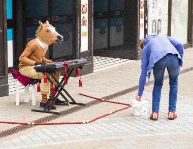 Man busking whilst wearing a horses head playing the keyboard clipart