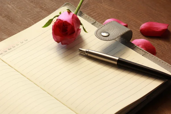 The book with pink rose and pen