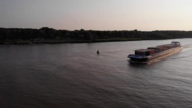 Akşamın erken saatlerinde Oude Maas boyunca seyahat eden kargo gemisinin iskele ve yay tarafının havadan görünüşü