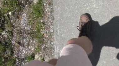 Güneşli bir günde Pavement Yolu 'nda bot giyen biri. - POV