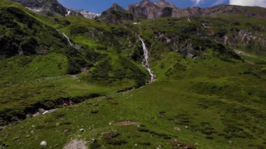 Avusturya, Kaprun 'daki yeşil manzaranın ortasındaki çağlayanın uzak görüntüsü. hava durumu