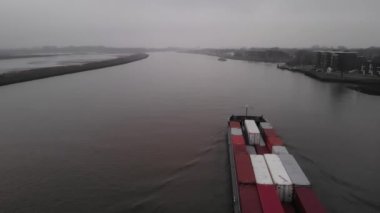 Konteynır gemisi sisli bir günde Hollanda nehrinde yol alıyor. Drone kamyonu vuruldu.