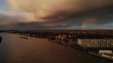 Gün batımında Hollanda 'da gökkuşağıyla birlikte Noord Nehri' nde yelken açan sanayi mavnası. - Hava.