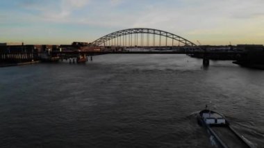 Altın saat boyunca bir tugayın sütunları arasında Hollandalı bir nehirde çamurlu bir şekilde yol alan tam dolu bir mavna. Drone kamyonu vuruldu.