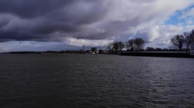 Hollanda, Puttershoek 'teki Oude Maas Nehri' nin Dalgalı Suyu Bulutlu. Tekne dramatik bir havada yelken açıyor. geniş çekim