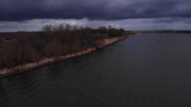 Hollanda, Puttershoek yakınlarındaki Oude Maas 'ta yüzen ördek sürüsüyle kasvetli bir nehir. - Hava Aracı Atışı.