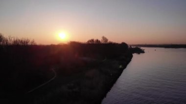 Hollanda, Güney Hollanda 'da gün batımında Oude Maas Nehri' ndeki Idyllic kasabası Puttershoek 'in üzerinde kızgın güneş ışığı. - Havadan çekim.