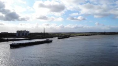 Hollanda, Puttershoek 'teki Pofuduk Beyaz Bulutlar ile Parlak Gökyüzü Altında Oude Maas Nehri' ne yelken açan sanayi mavnaları. - Hava.