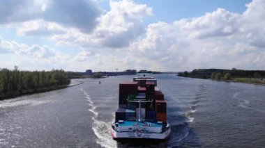 Konteynır gemisi Hollanda 'nın başkenti Puttershoek' te Oude Maas River Under Summer Sky 'da yol alıyor. hava durumu