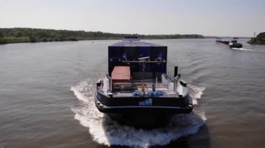 Güneşli bir günde Sakin Nehirde Seyir halindeki ticaret gemisinden su sıçratın. - Havadan çekim.