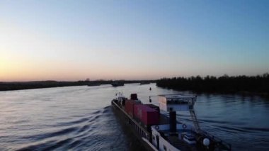 Gündoğumunda Kargo Gemisi Nehirde. Meta Maria, Hollanda 'da Oude Maas' ta yelken açıyor. İHA yükseliyor