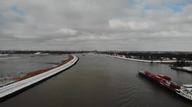 Hollanda, Güney Hollanda 'da kış boyunca bulutların altında, Serene Noord Nehri üzerinde seyir eden konteynırları olan sanayi gemisi. - Havadan Geniş Atış