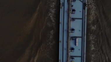 Yoğun yüklü mavi tanker, koyu renkli bir nehirde ilerlerken radar kullanıyor. Yukarıdan drone kulesi atışı.
