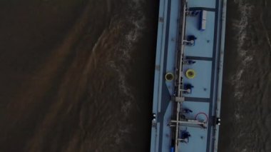 Yoğun yüklü mavi tanker, koyu renkli bir nehirde ilerlerken radar kullanıyor. Yukarıdan drone atışı.
