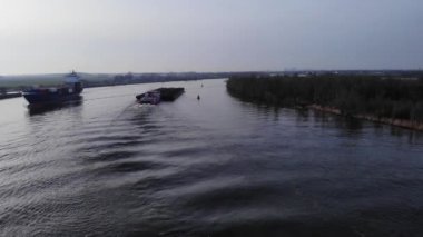 Yük gemileri suda. Nehrin yukarısındaki hava manzarası. Drone yükseliyor.