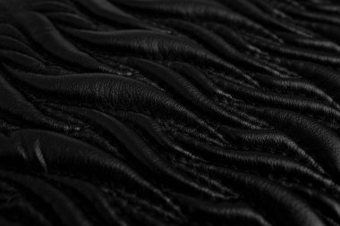 Siyah deride dikişleri olan soyut desenler, yeni bir çantada süslemeli alev şekilleri, yumuşak odaklanma.