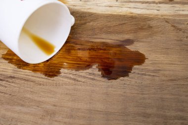 Meşe ağacından masa arkaplanındaki beyaz seramik bardaktan kahve döküldü.  