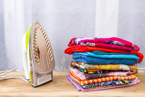 Renkli, katlanmış çamaşır ya da eşarpların yanında yanık izleri olan ütü.