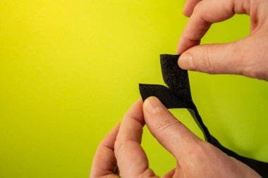 Yeşil arka planda kadın parmaklarının açtığı, kanca ve ilmek bantlı cırt cırtlı bant.