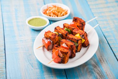 Paneer Tikka Kabab - Hint Tandoori peynir şişleri, malai paneer tikka / biber paneer malai paneer kabab, servis beyaz tabak Barbekü sopa ve renkli kırmızı biber ve soğan, yeşil sos ile