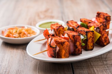 Paneer Tikka Kabab - Hint Tandoori peynir şişleri, malai paneer tikka / biber paneer malai paneer kabab, servis beyaz tabak Barbekü sopa ve renkli kırmızı biber ve soğan, yeşil sos ile