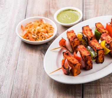 Paneer Tikka Kabab - Hint Tandoori peynir şişleri, malai paneer tikka / biber paneer malai paneer kabab, servis beyaz tabak Barbekü sopa ve renkli kırmızı biber ve soğan, yeşil sos ile