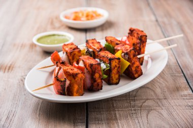 Paneer Tikka Kabab - Hint Tandoori peynir şişleri, malai paneer tikka / biber paneer malai paneer kabab, servis beyaz tabak Barbekü sopa ve renkli kırmızı biber ve soğan, yeşil sos ile
